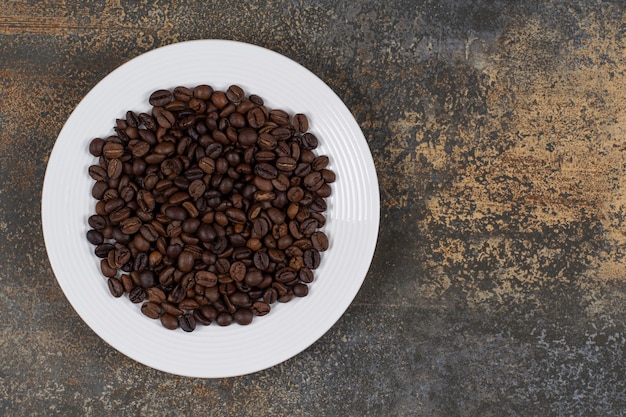 Roasted coffee beans on white plate.