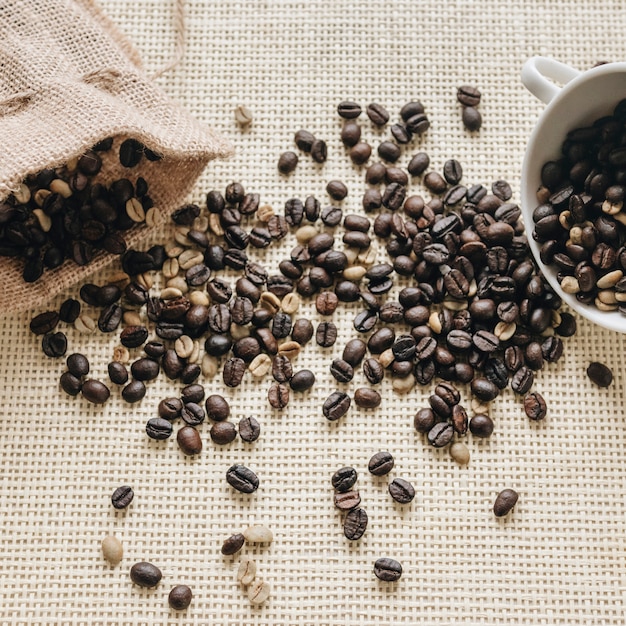 Foto gratuita chicchi di caffè tostati con sacco e tazza in ceramica