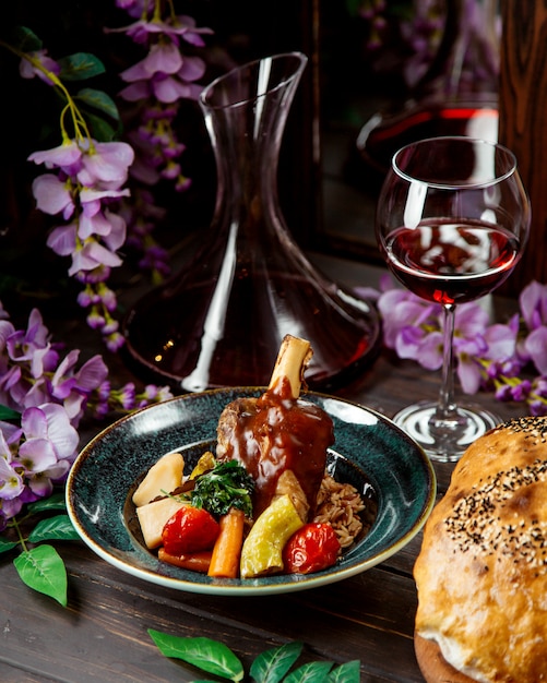 Roasted lamb garnished with tomato sauce served with bulgur and vegetables