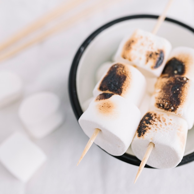 Roasted marshmallows on stick in small cup