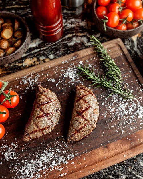 Carne arrostita sotto forma di torte con le spezie su un bordo di legno