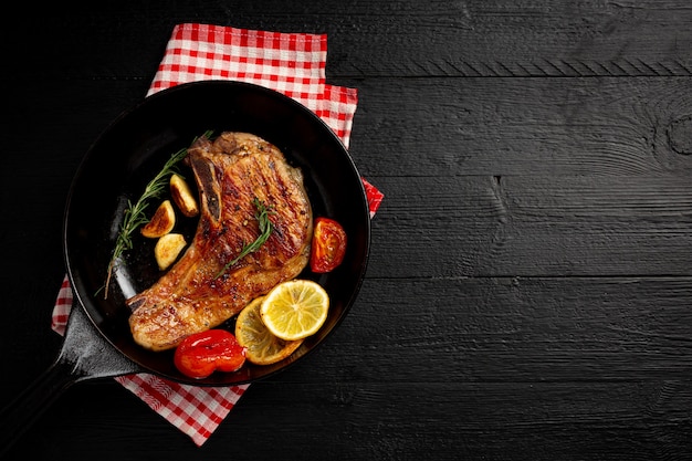 Roasted pork steak on the dark wooden surface.