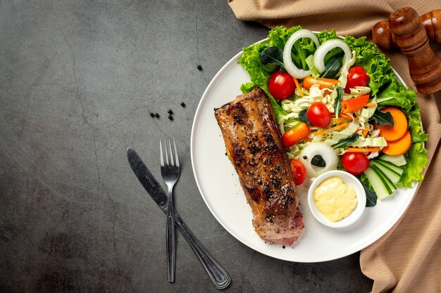 Roasted pork steak and vegetables on plate.