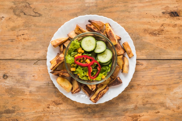 Roasted potato slice and fresh vegetables in bowl on white plate