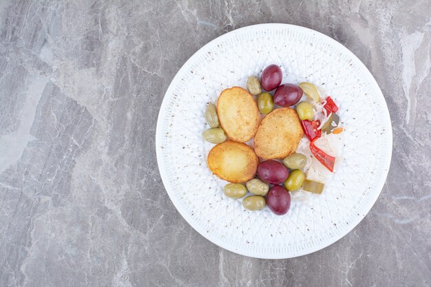 Roasted potato and various pickles on white plate.