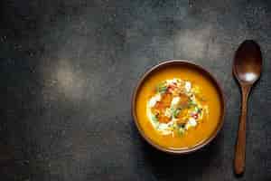 Free photo roasted pumpkin and carrot soup with cream, seeds and fresh green in ceramic bowl. top view