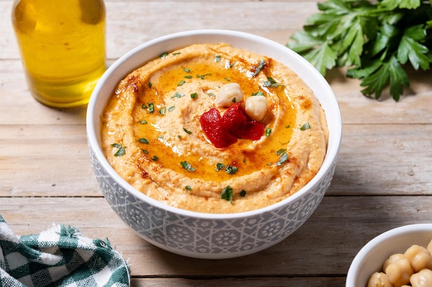 Free photo roasted red pepper hummus in white bowl on wooden table