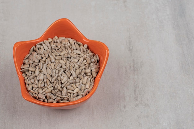 Roasted sunflower seeds in orange bowl.