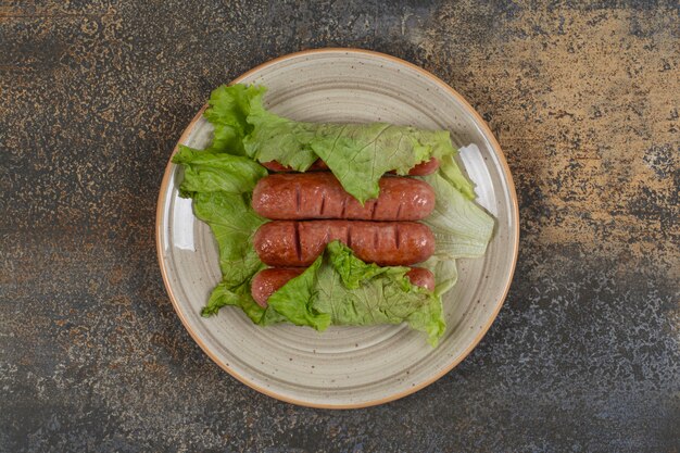 Roasted tasty sausages on ceramic plate.