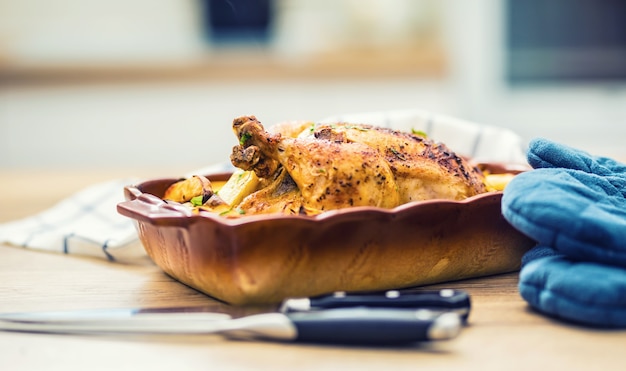 Жареный цыпленок целиком с картофелем в форме для запекания. вкусная еда дома на кухонном столе.