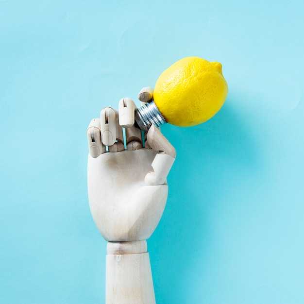 Free photo robot hand holding a lemon bulb