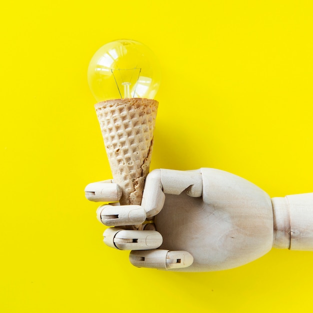 Free photo robot hand holding a light bulb ice cream