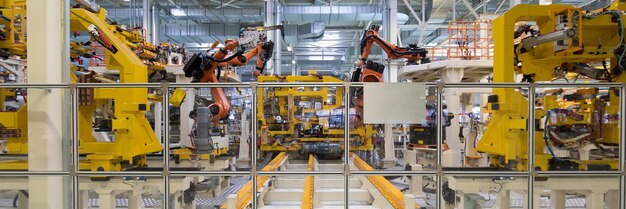 Роботизированное оборудование собирает автомобили на производственной линии Длинноформатная съемка автомобилей Автомобильный завод Баннер