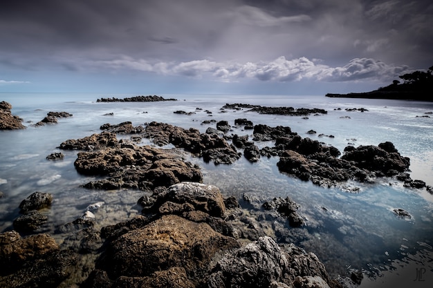 Rock formations in the sea under the cloudy sky