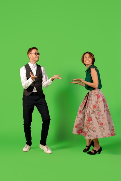 락앤롤. 구식 구식 된 젊은 여자 춤 녹색 스튜디오 배경에 고립. 세련 된 젊은 남자와 여자.