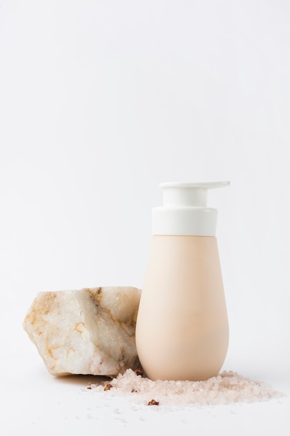 Rock salt and soap dispenser against white background