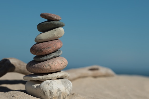 Rocks balanced perfectly on top of each other on sand showing the concept of harmony