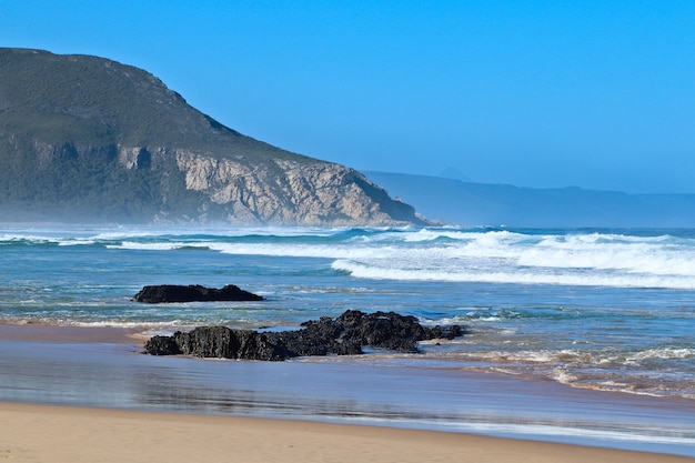 Foto gratuita rocce sulla spiaggia dal bellissimo oceano con le montagne