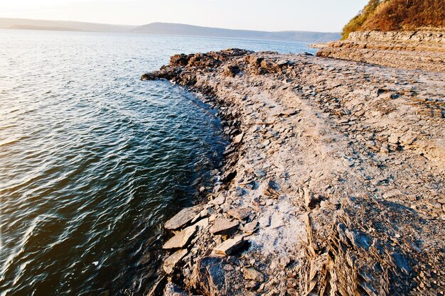 Rocky beach of great lake in sunset