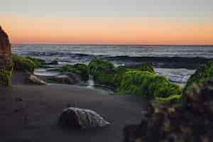 Foto gratuita spiaggia rocciosa al tramonto