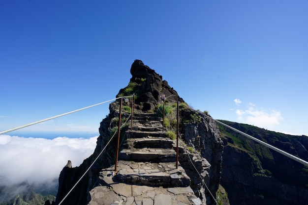 澄んだ空を背景にした山頂に向かう岩だらけの小道