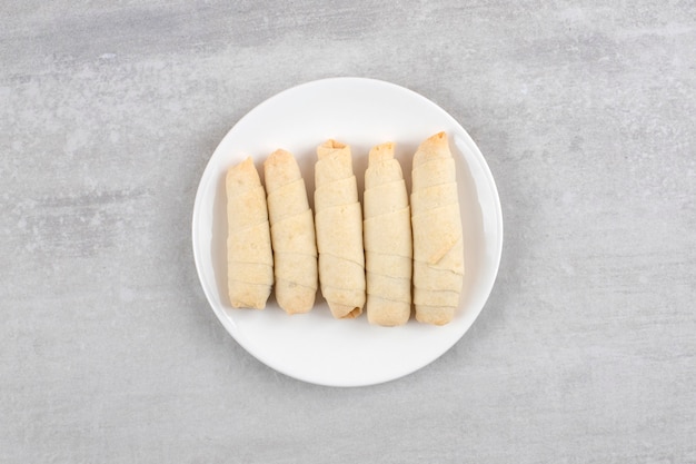 Roll cookies on a plate, on the marble table. 