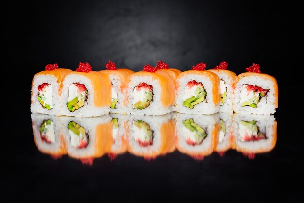 Roll Philadelphia made of salmon, cucumber, nori, pickled rice, cheese, masago caviar