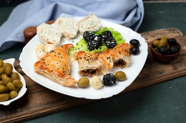 Roll salad with pastry and olives in a white plate