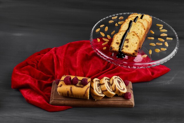 Rollcake slices with pie slices on a red tablecloth. 