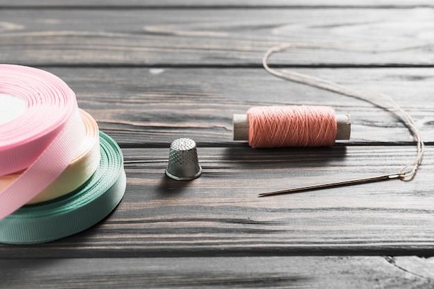 Rolled colorful ribbons and sewing item on wooden table