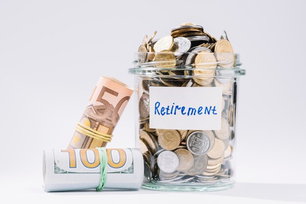 Rolled up banknotes and retirement container full of coins on white background