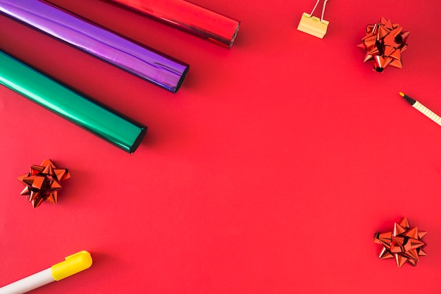 Rolled up gift paper; bow; felt pen and bulldog pin on red background