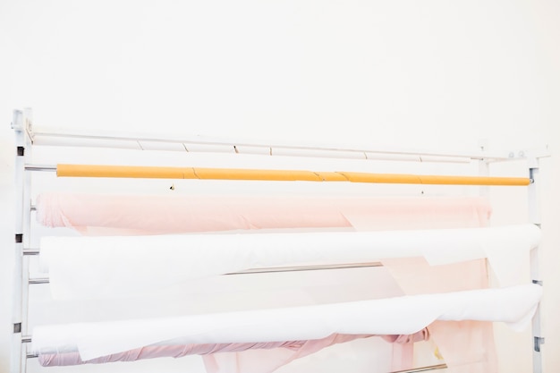 Free photo rolled up pink and white fabrics in tailor shop