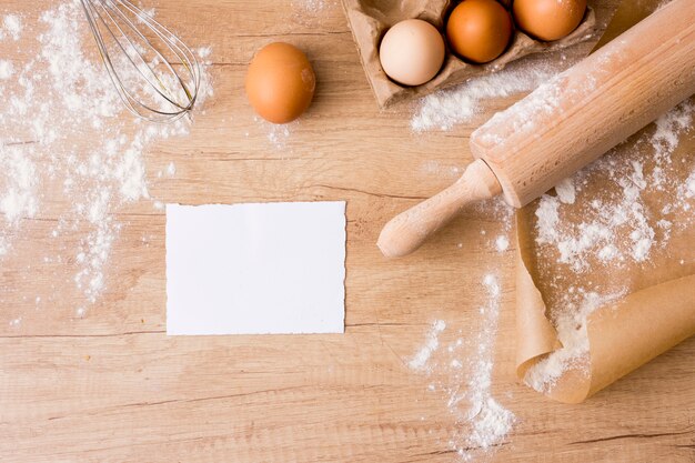 Rolling pin with eggs in rack, paper and flour