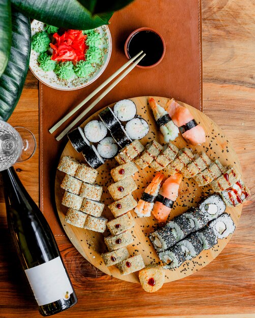 Rolls of fish on the brown round surface along with black sauce a top view on the wooden surface