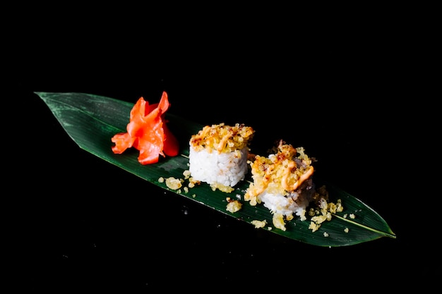 Rolls with crackers in the top on a green leaf with ginger in dark space.