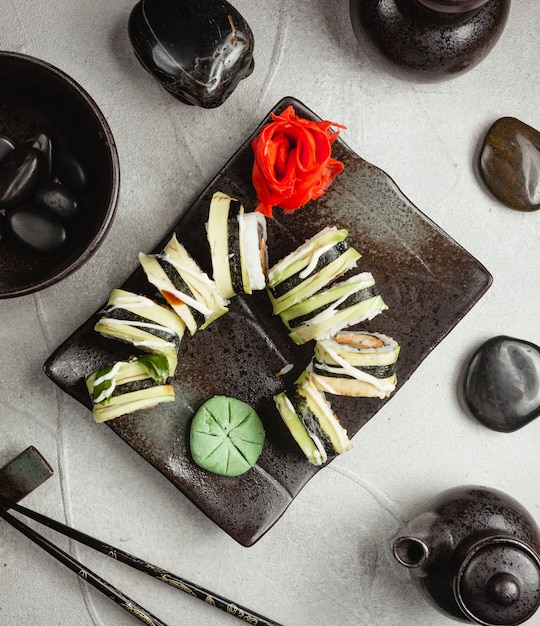 Rolls with ginger and wasabi on a black board.