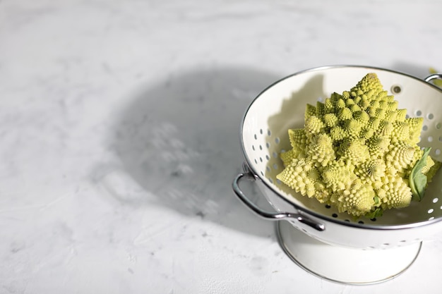 Romanesco cabbage in a white colander on a gray background BIOVegetables Copy Space