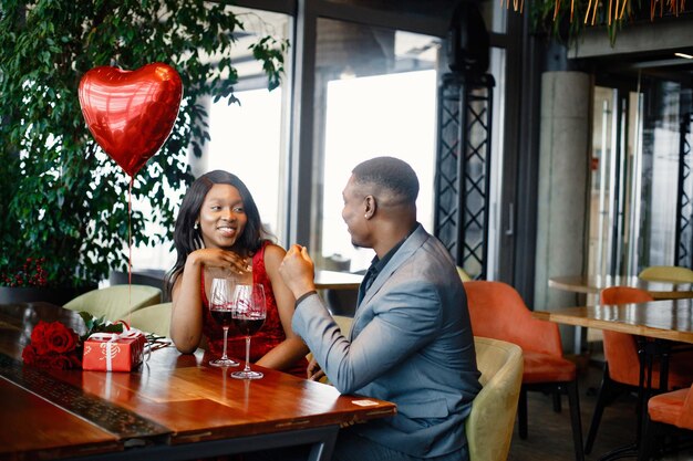 Romantic black couple sitting at restaurant wearing elegant clothes