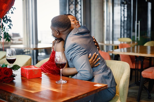 Romantic black couple sitting at restaurant wearing elegant clothes