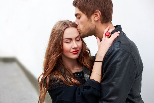 Romantic boy hugging and kissing his girlfriend's forehead