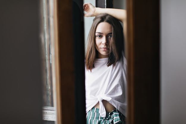 Romantic caucasian woman with dark hair. Indoor portrait of graceful female model standing with hands up.