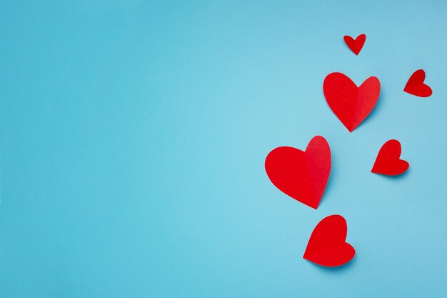 Romantic composition made with red hearts on blue background with copyspace for text