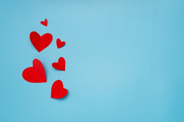 Romantic composition made with red hearts on blue background with copyspace for text