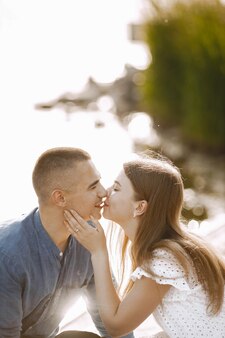 ロマンチックなカップルのボーイフレンドとガールフレンドが湖の近くでキスします。男と女がお互いを見てキスをする