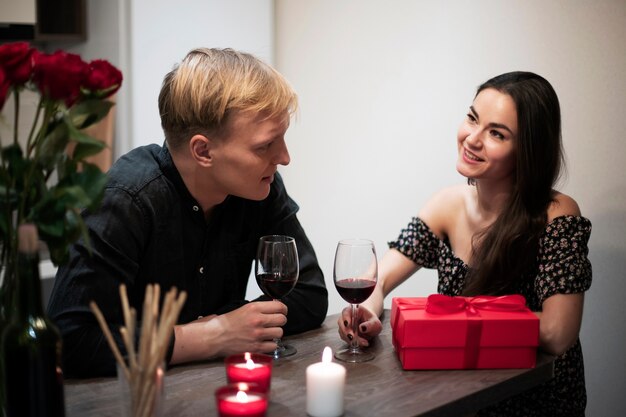 집에서 와인과 선물로 발렌타인 데이를 축하하는 로맨틱 커플