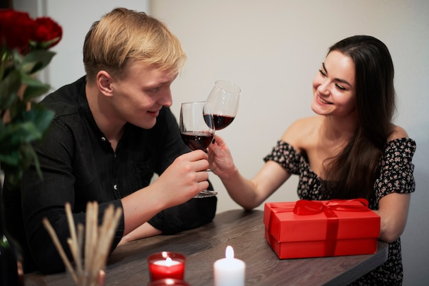 Coppia romantica che celebra il giorno di San Valentino a casa con vino e regalo