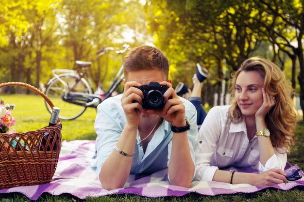 公園でピクニックの時間に写真の写真をやっているロマンチックなカップル。