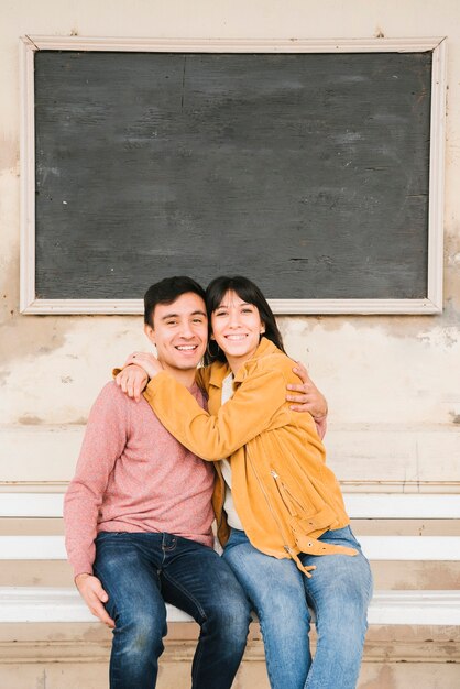 Free photo romantic couple embracing and sitting on bench and laughing