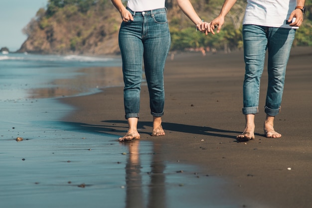 Coppia romantica tenendo la mano e camminando sulla spiaggia